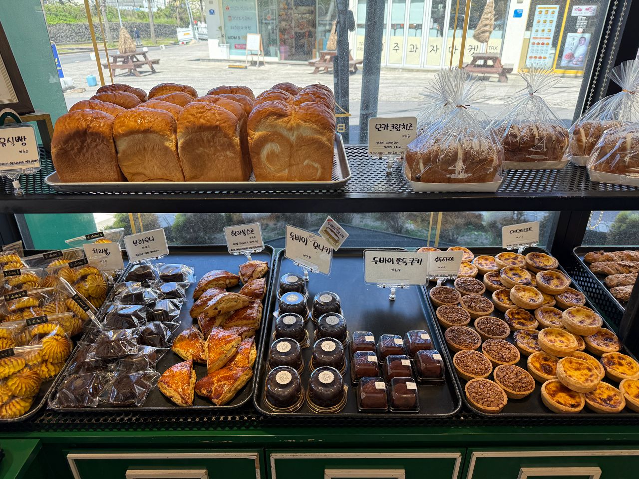 濟州島大蒜麵包 Audrant Bakery 攻略|咸德本店招牌大蒜麵包、出爐時間、分店資訊與怎麼帶回台灣 - 第10張圖 Audrant Bakery 陳列架上的吐司、蛋塔、可麗露、杜拜巧克力等烘焙品項