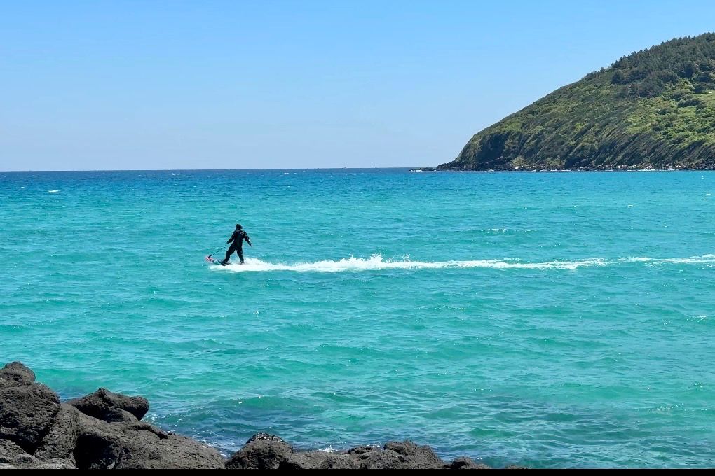 咸德海水浴場攻略|濟州島東岸自駕第一站,停車、海景、日落全收錄 - 第6張圖 有人在咸德海水浴場玩水上設施