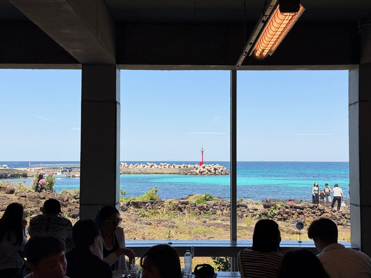 從濟州島倫敦貝果博物館樓下座位透過落地窗看出去的海景與紅色燈塔